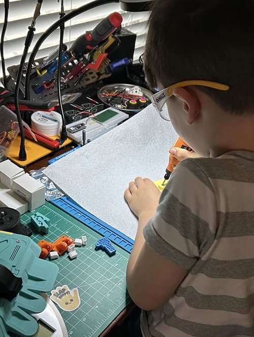 A young builder working on a combat robot at a workbench
